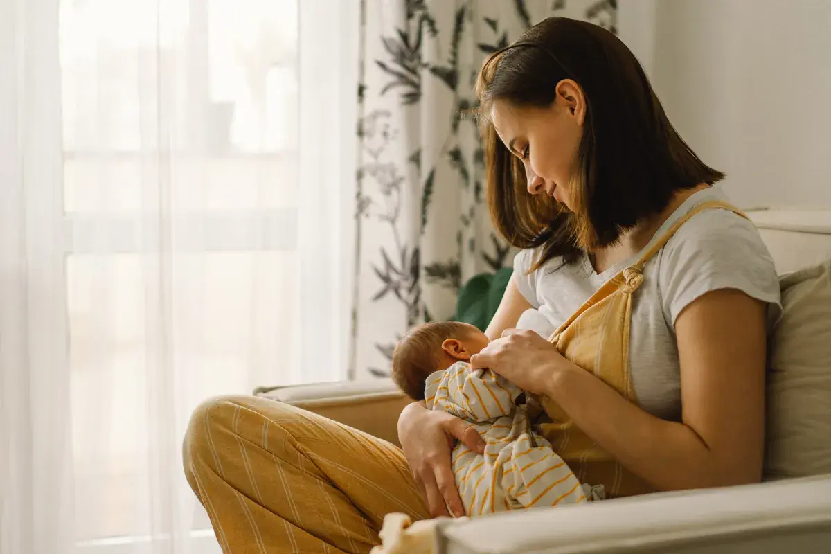 Mother breastfeeding her infant on a sofa